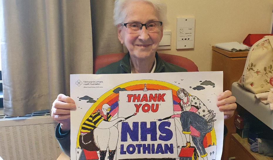 Patient in hospital holding up coloured in drawing to say Thank You NHS Lothian
