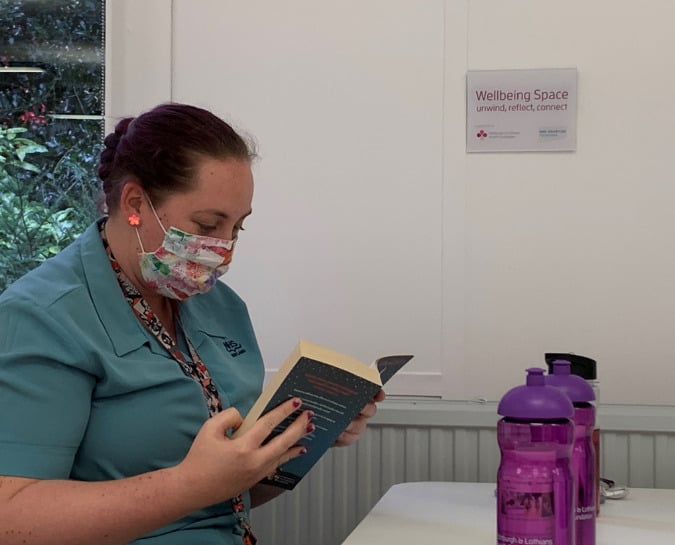 NHS Lothian Staff member sitting in the wellbeing space reading a book