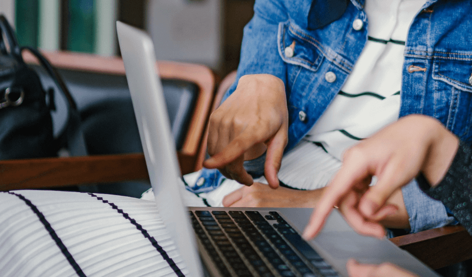 two people pointing at a laptop