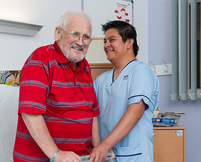 Nurse helping elderly patient with walking apparatus