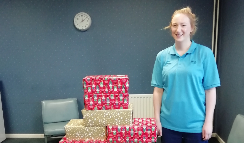 NHS Lothian nurse standing beside a bundle of wrapped Christmas presents