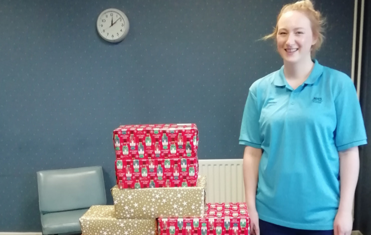 NHS Lothian nurse standing beside a bundle of wrapped Christmas presents