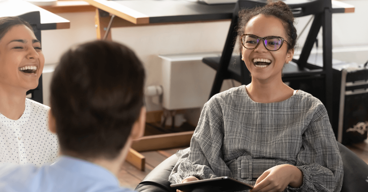 Work Colleagues sat together in an office smiling