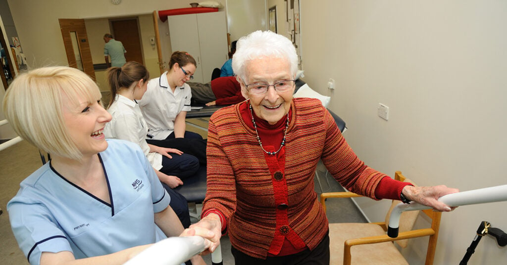 Nurse helping elderly up the stairs inside ward