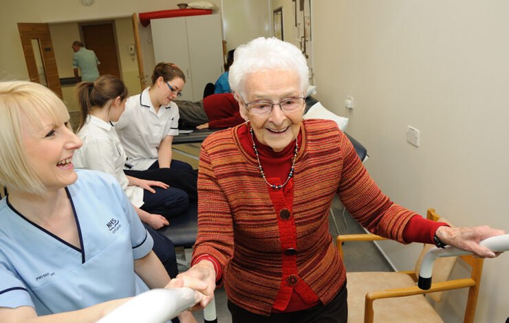 Nurse helping elderly up the stairs inside ward