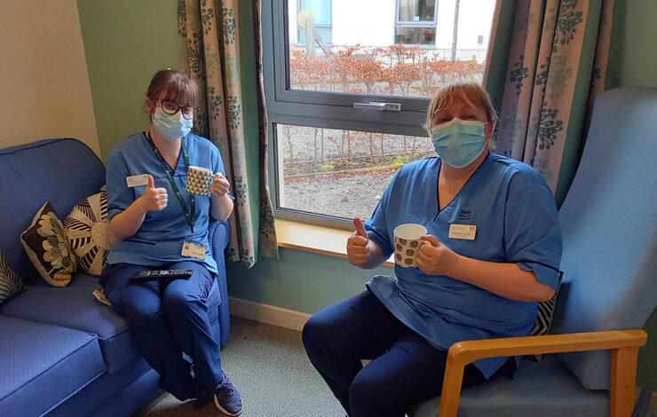 Nurses sitting down holding thumbs up