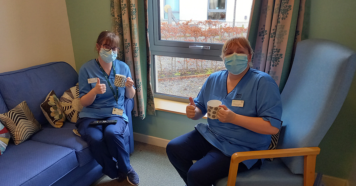 Nurses sitting down holding thumbs up