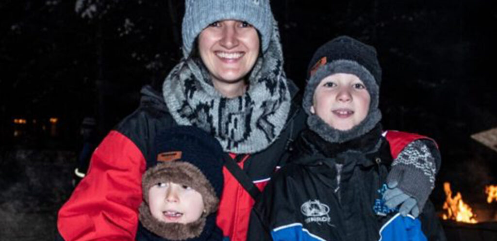 Michaelaghs family hugging and smiling in winter clothes in front of bonfire