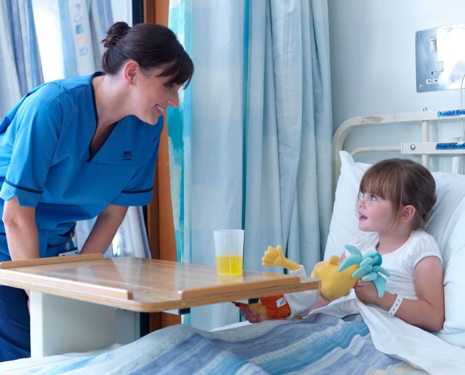 Nurse talking to child sat in a hospital bed