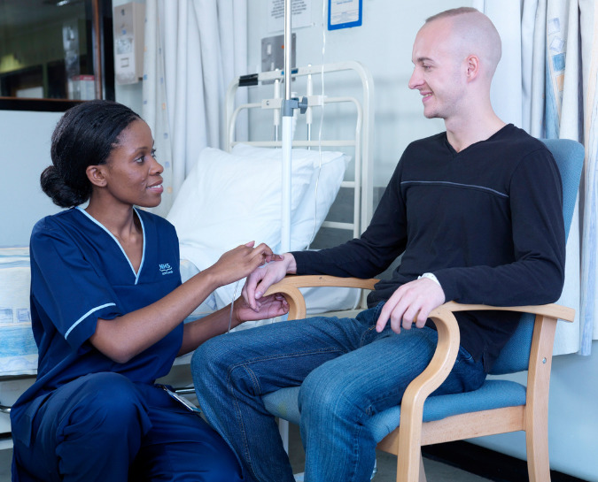 Nurse speaking to a patient who is sat in a chair