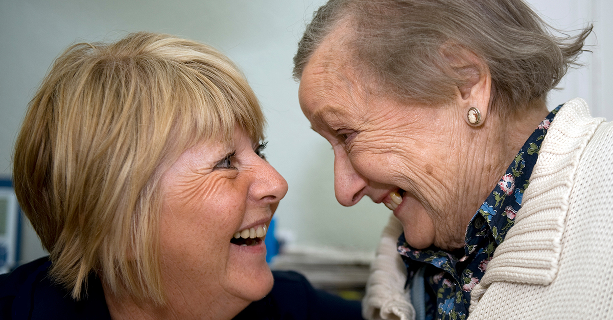Nurse and elderly patient smiling at each other