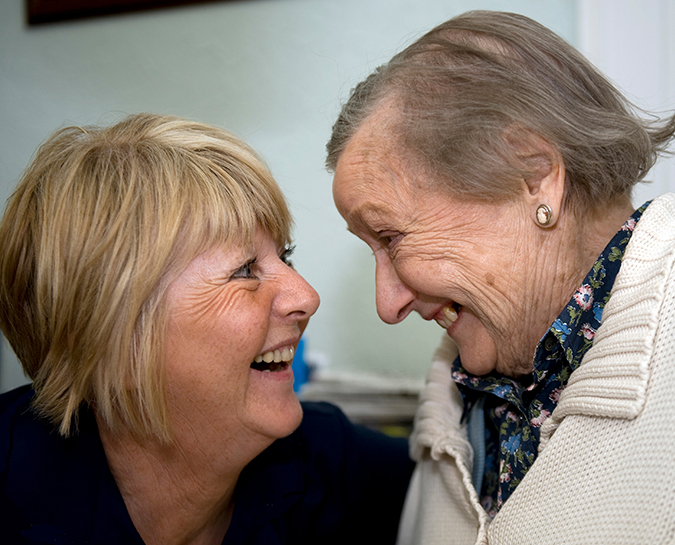 Nurse and elderly patient smiling at each other