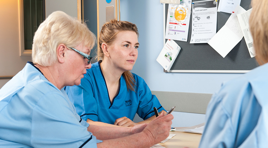 Nurses sat down at table with pen and paper in thought