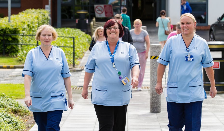 Three nurses smiling and walking in the outdoors