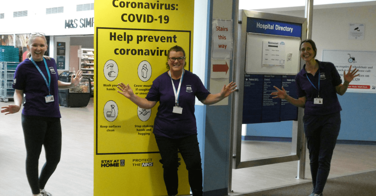 Volunteers stood in front of a COVID-19 guidance sign