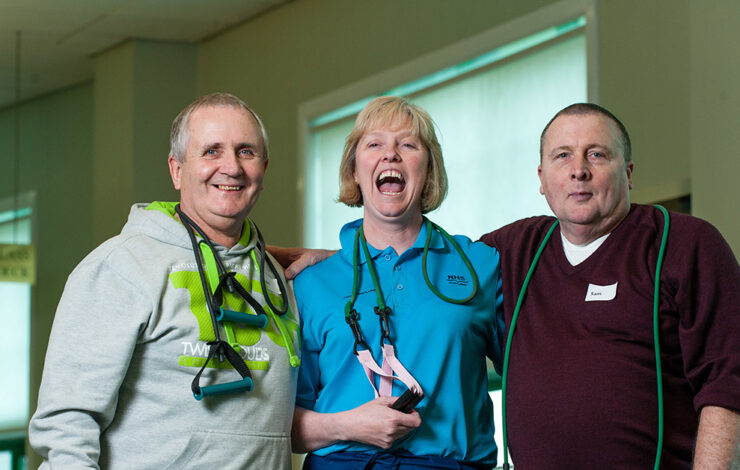 Hospital staff with fitness equipment hanging on shoulders embracing and smiling