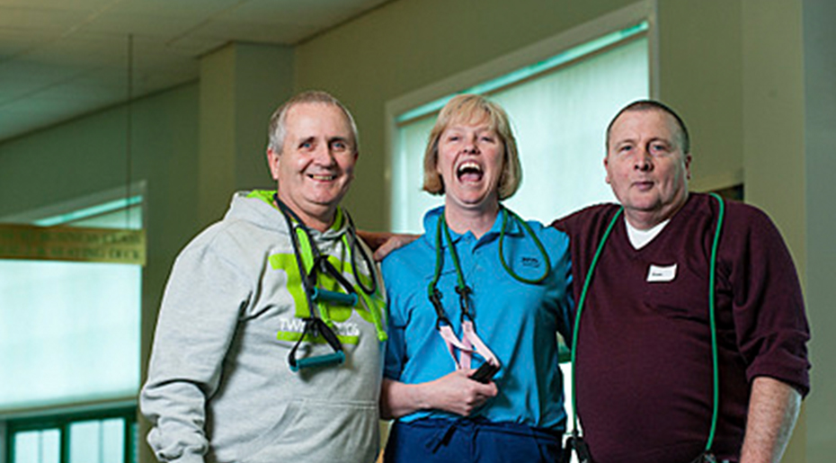 Hospital staff with fitness equipment hanging on shoulders embracing and smiling