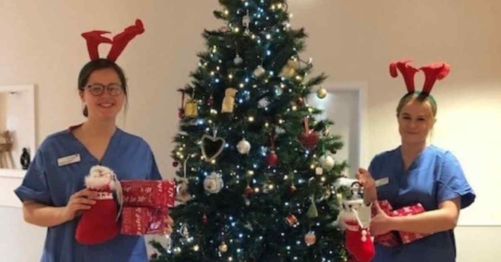 NHS Lothian staff around the Christmas tree with presents for patients