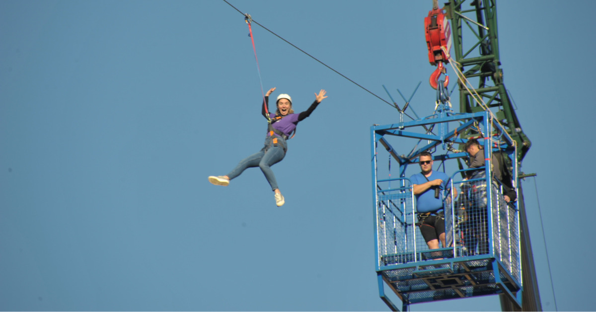 Clare smiling and waving as she goes on the zipslide
