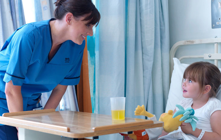 Nurse smiling at a child patient in a hospital bed
