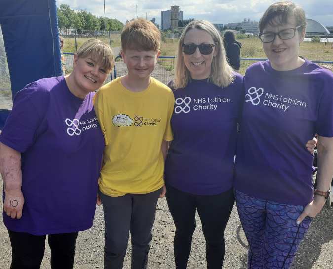 Four NHS Lothian Charity Champions smiling at the camera. 4 are wearing a purple NHS Lothian Charity purple t-shirt and the other person is wearing a yellow Fighting Against Cancer Edinburgh t-shirt.