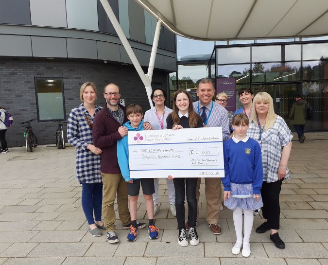 Molly MacFarlane and her family presenting a cheque to support scoliosis research