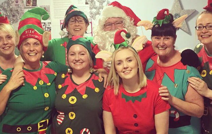 7 members of NHS Lothian staff from the Labour Ward at St Johns smiling at the camera dressed as elves with Santa