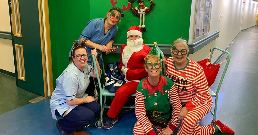 5 members of NHS staff sat outside the Vascular Surgery ward at the Royal Infirmary of Edinburgh dressed up as elves and Santa.