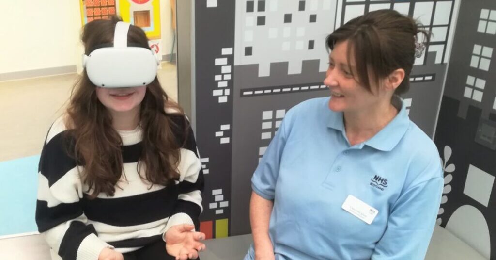 Isla watching the virtual reality film beside an NHS Lothian member of staff