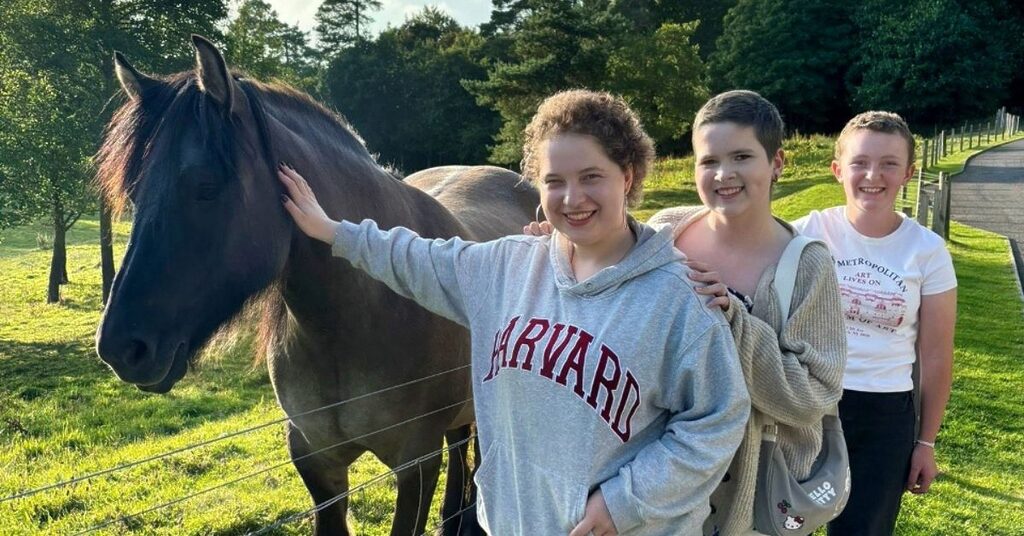 Three children standing beside a horse in a field