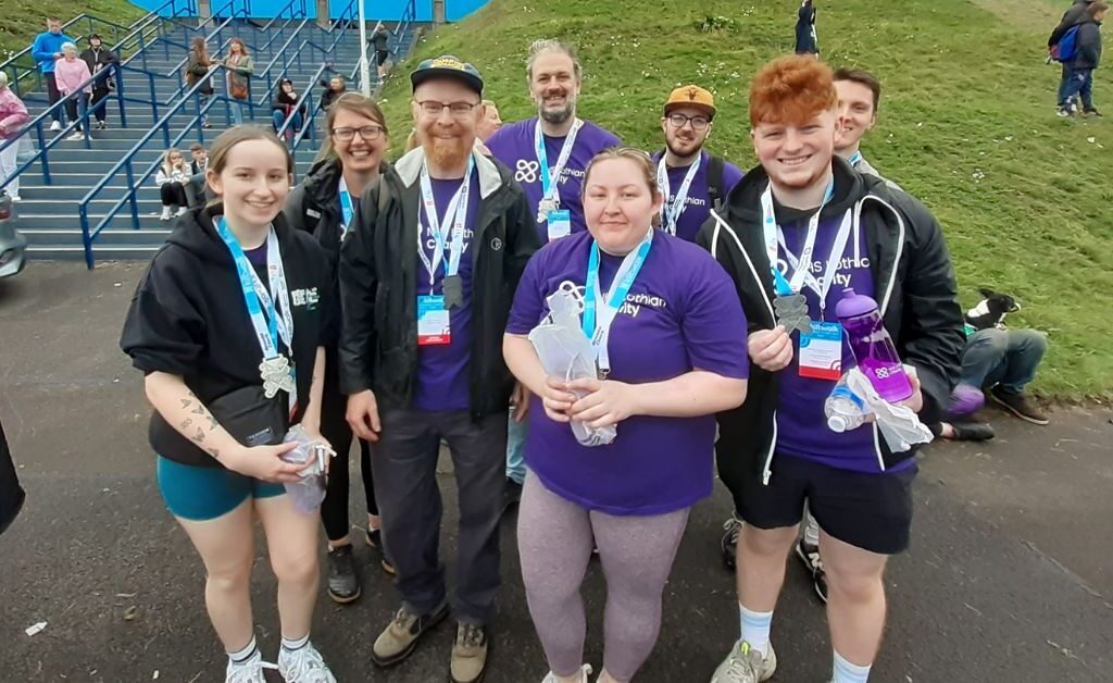 Eight Kiltwalk Charity Champions stood at the end of the Kiltwalk in their NHS Lothian t-shirts and finishers medal smiling