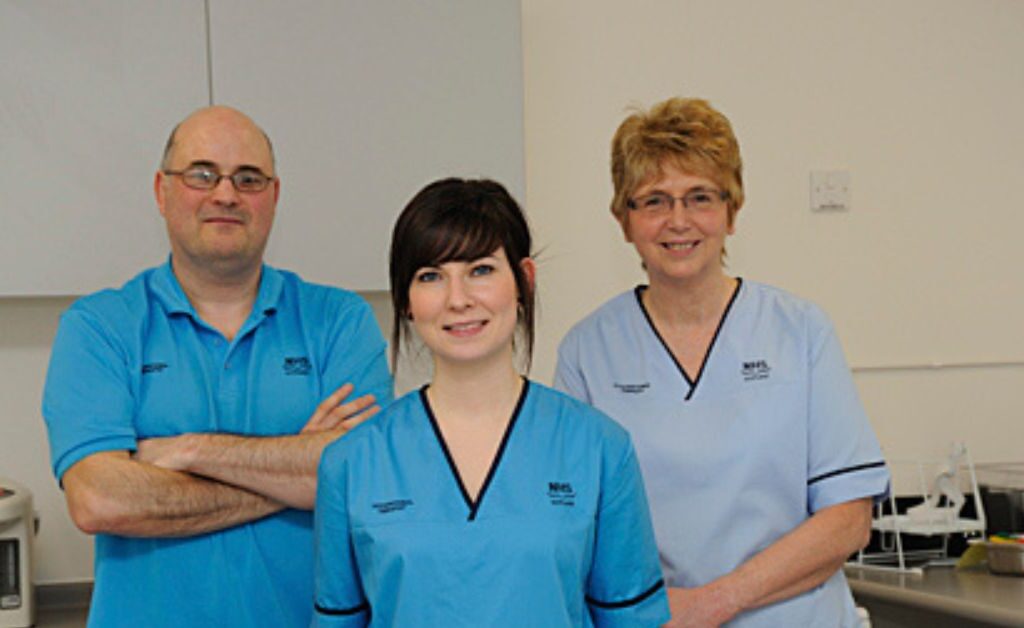 Three NHS Staff members in uniform facing the camera
