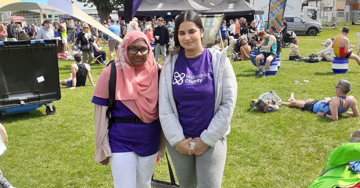 Two volunteers stood together at the Edinburgh Marathon Festival wearing NHS Lothian Charity purple t-shirts