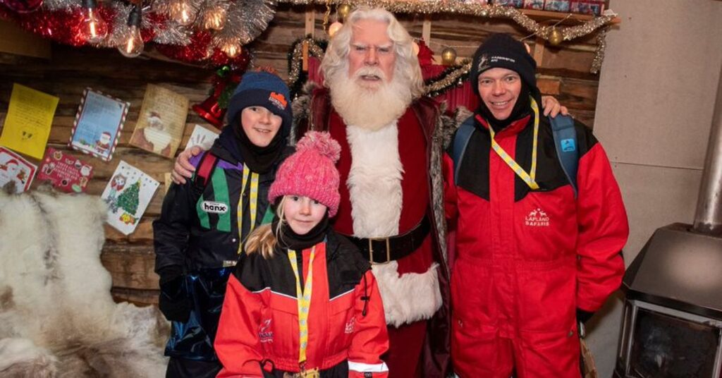 Santa and visitors smiling for the camera in Lapland at Christmas during the FACE annual trip to support families impacted by cancer
