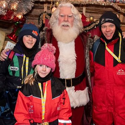 Santa and visitors smiling for the camera in Lapland at Christmas during the FACE annual trip to support families impacted by cancer
