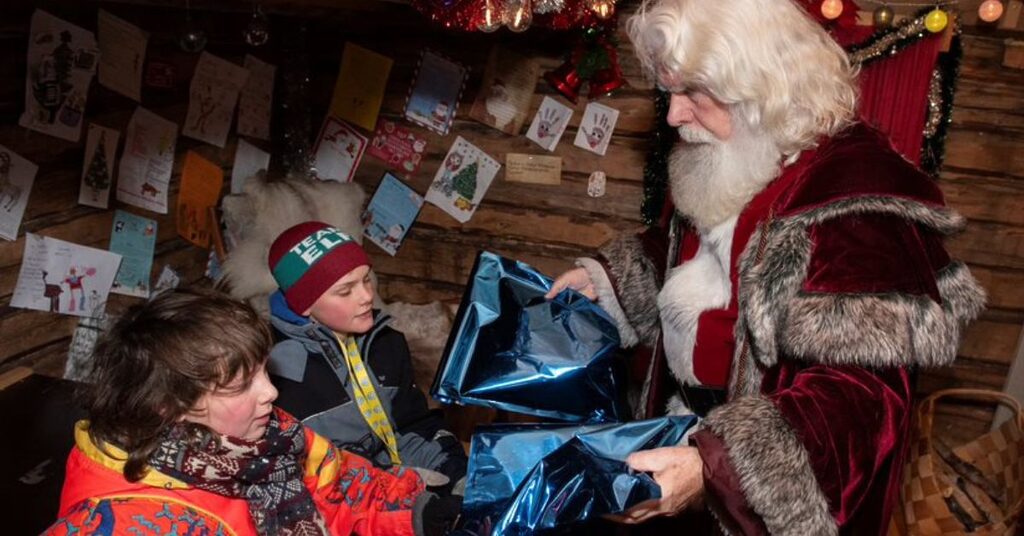 Featured image for Lapland raffle. Santa giving children presents in Lapland at Christmas during the FACE annual trip to support families impacted by cancer