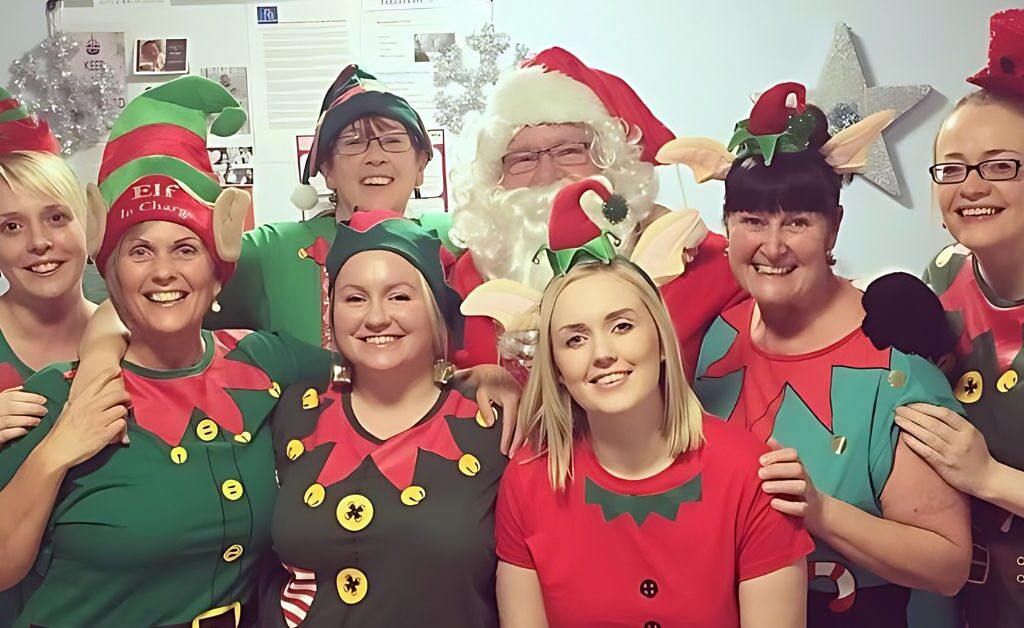 Eight members of NHS staff smiling at the camera wearing elf costumes