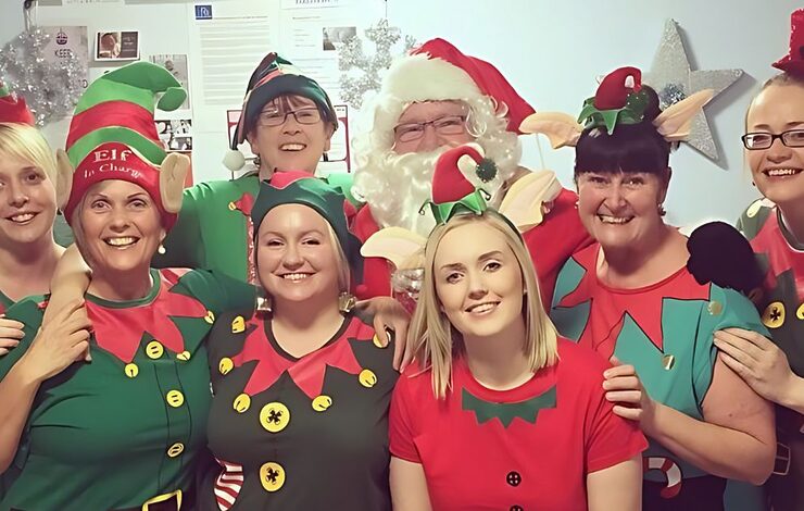 Eight members of NHS staff smiling at the camera wearing elf costumes