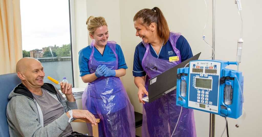 two members of staff talking to a patient as he undergoes treatment