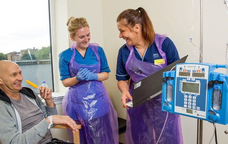 two members of staff talking to a patient as he undergoes treatment