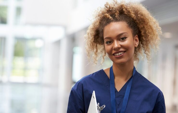 nurse in blue uniform with a clipboard facing the camera