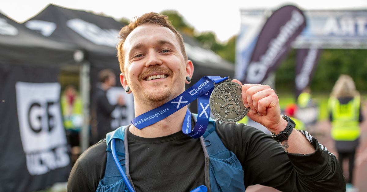 Matt from the Gym Group holding up his ultra marathon medal