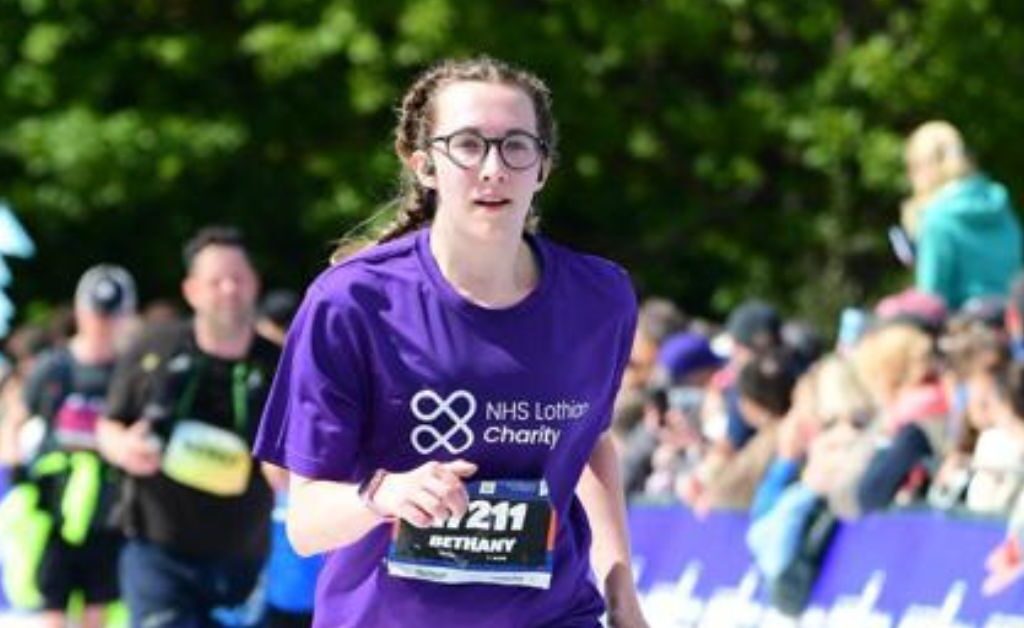 EMF runner, Beth, running past the crowds in her NHS Lothian Charity t-shirt