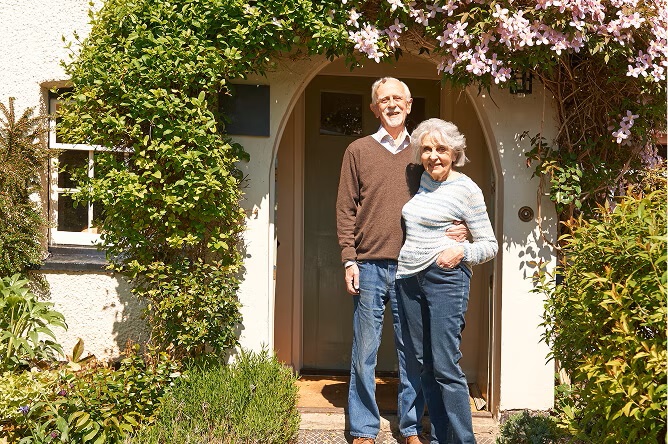 woman and man standing at a door with plants growing round it