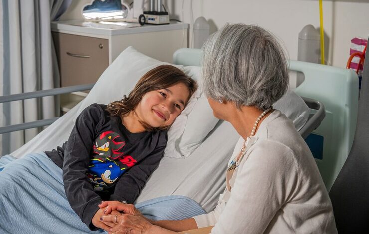 boy in hospital bed smiling at his grandparent