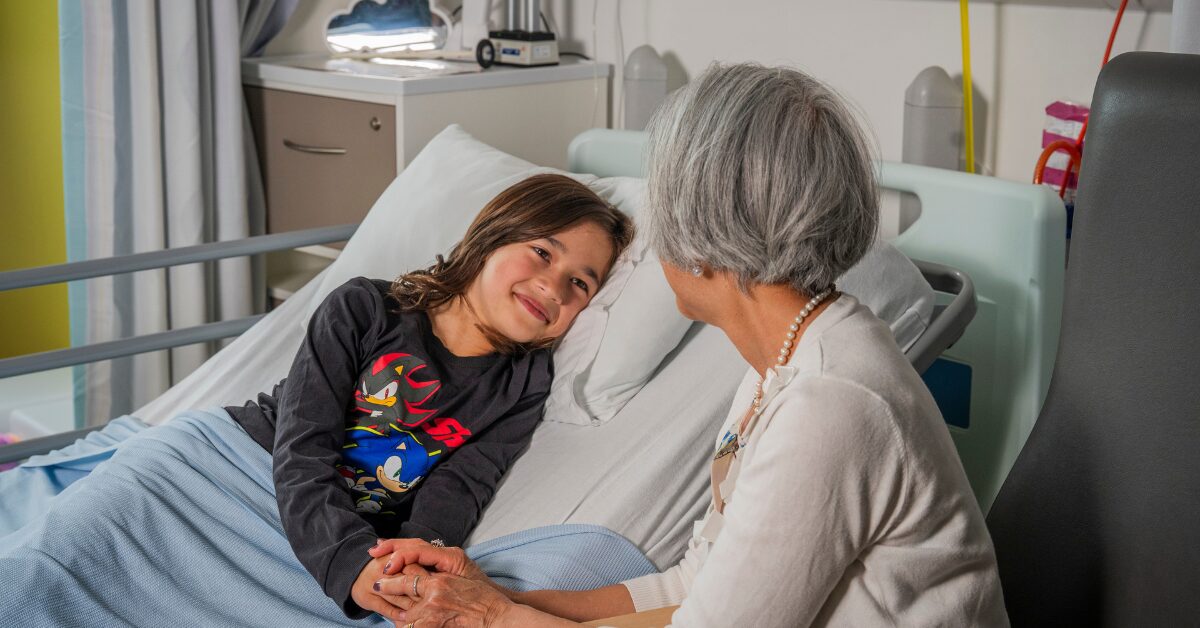 boy in hospital bed smiling at his grandparent