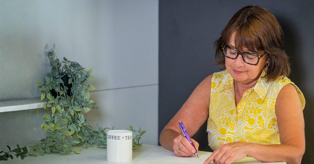 Lady with glasses signing a piece of paper