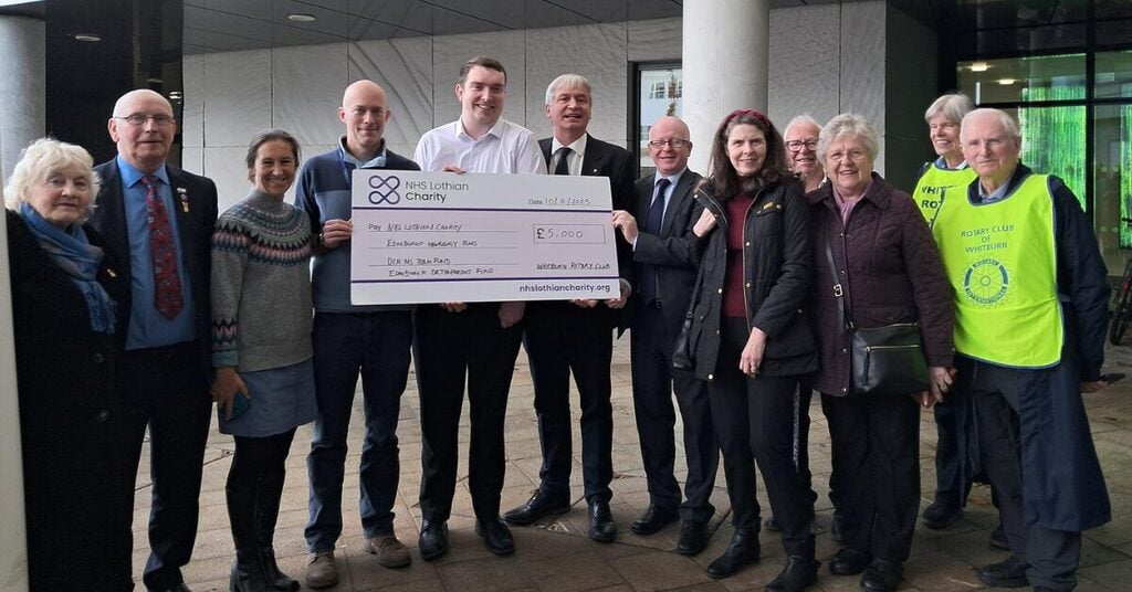 group of adults holding a large cheque