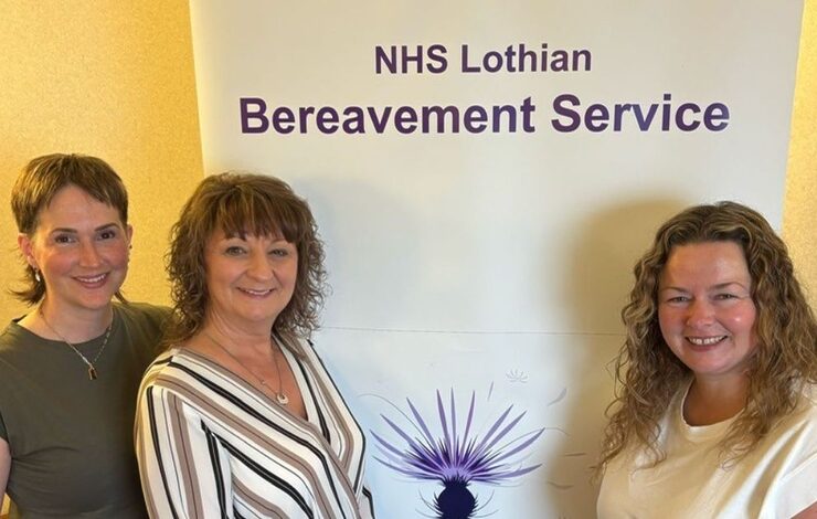 three staff from bereavement services standing in front of a banner