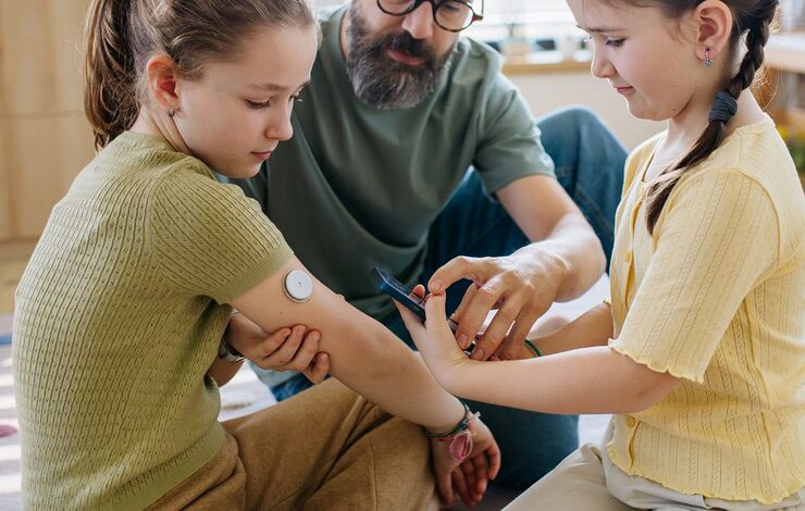 parent showing children how to use a diabetes monitor